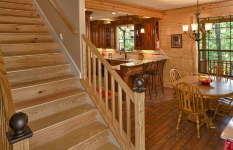 The image showcases a rustic yet elegant kitchen and dining area inside one of our finely-crafted log homes.