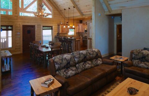 The image showcases a beautifully crafted living room and dining area within our premium log cabin home.