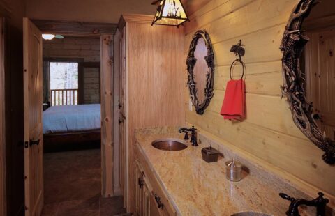 The image displays a beautifully designed bathroom in one of our log homes, fitted with two sinks and a mirror.