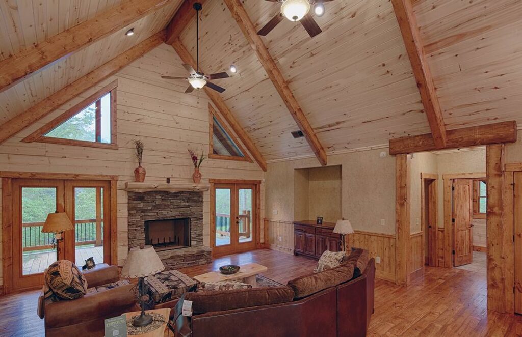 The image showcases a cozy living room inside our log home, featuring stunning wood ceilings and an inviting fireplace.