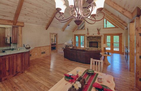 The image showcases a beautifully designed living room and dining room area in one of our incredibly crafted log cabins.