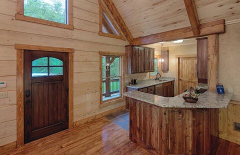 The image showcases a cozy, well-equipped kitchen nestled within one of our charmingly rustic log cabins.