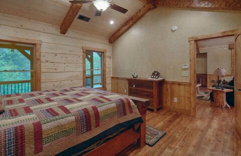 The image showcases a cozy bedroom in one of our manufactured log cabins, featuring wooden floors and a comfortable bed.