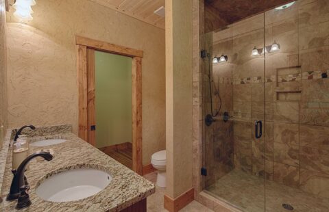 The image showcases a luxuriously designed bathroom in our log home, featuring two elegant sinks and a spacious walk-in shower.