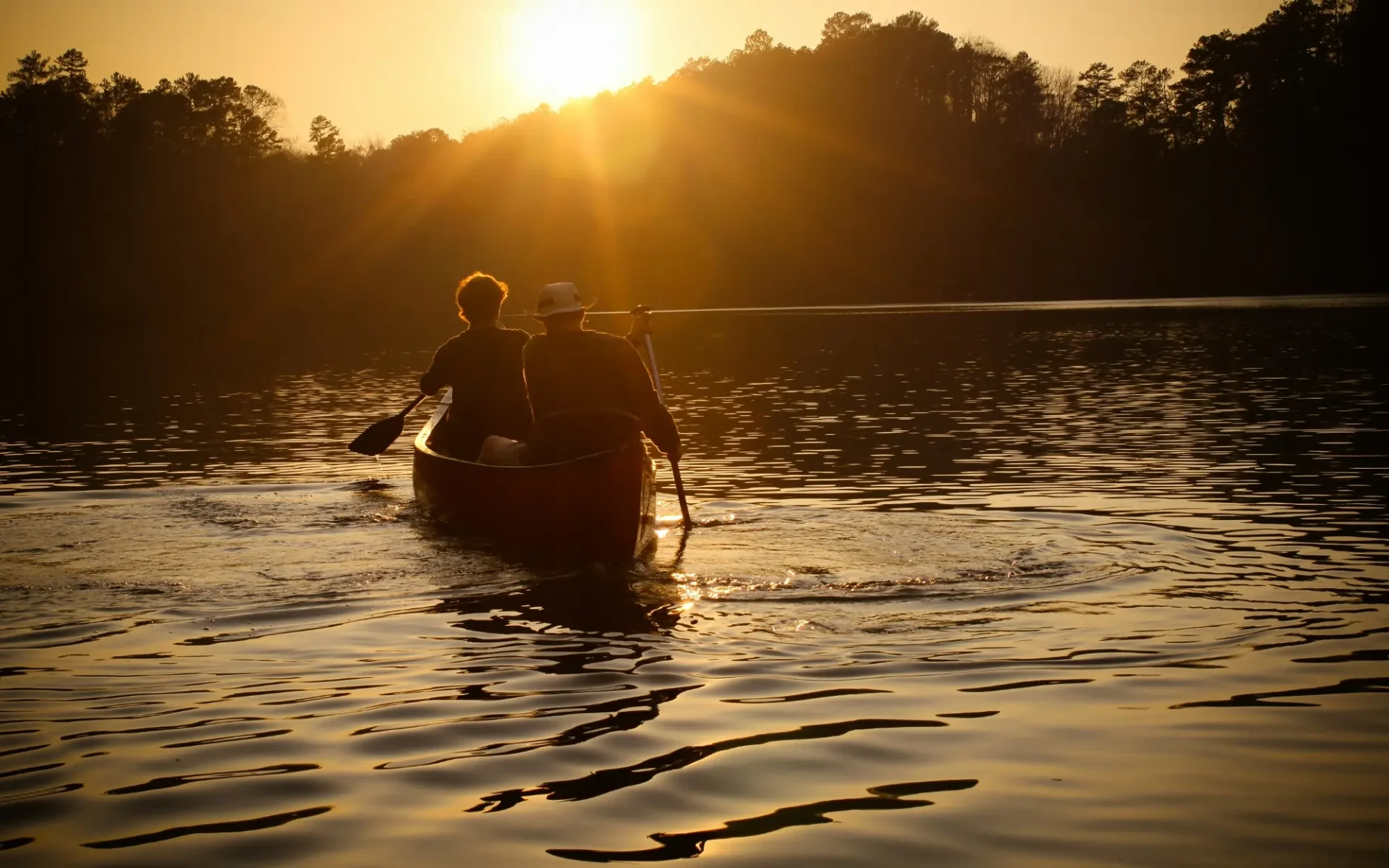 Two men paddle a canoe in Birmingham, Alabama at sunset.