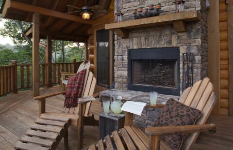 The image showcases a beautifully crafted wooden deck featuring a cozy, built-in fireplace from our log home collection.