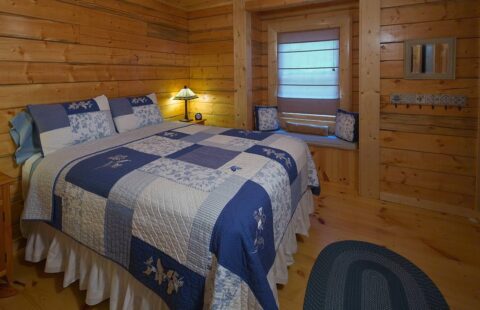 Our log cabin showcases a cozy interior featuring a blue and white quilted bed.