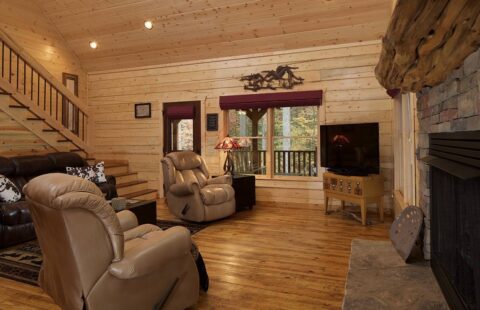 The image showcases a homey and inviting living room within one of our beautifully crafted log cabins, complete with a warm, crackling fireplace.