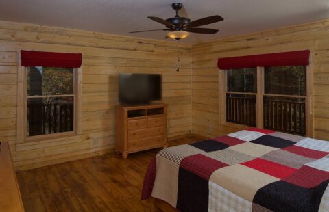 The image illustrates a cozy bedroom within our log cabin, furnished with a comfortable bed and a television for modern convenience.