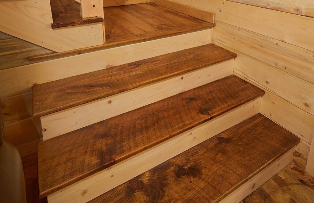 The image depicts a beautifully crafted wooden staircase set within the rustic charm of our superbly designed log cabin.