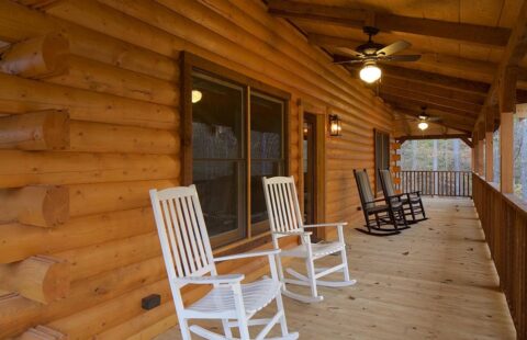 A cozy log cabin showcases a porch adorned with two inviting rocking chairs.