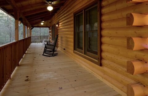 A rustic, inviting porch of a log cabin, adorned with cozy rocking chairs.