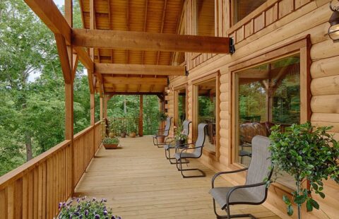 The image showcases a beautifully crafted porch of one of our log cabins, furnished with comfortable chairs and a rustic table.