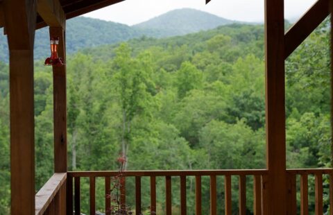 The image showcases a breathtaking mountain vista as seen from the porch of our beautifully crafted log cabin.