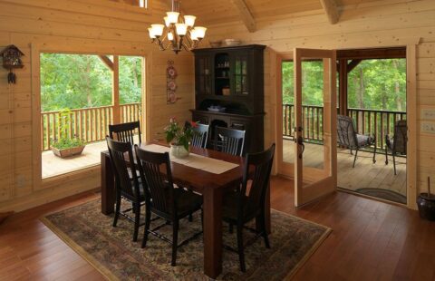 The image showcases a beautifully crafted dining room within a log cabin, exuding rustic charm and warmth.