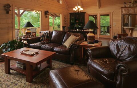 The image showcases a cozy, spacious living room within a beautifully crafted log cabin.