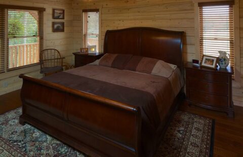 The image showcases a spacious bedroom within one of our manufactured log cabins, prominently featuring a comfortable king-size bed.