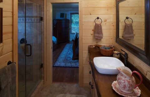 The image features a rustic yet stylish bathroom in one of our log cabins, equipped with a sink and shower.