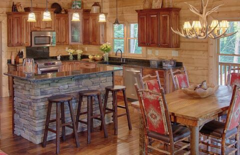 The image showcases a rustic yet modern kitchen set-up within a beautifully built log cabin, complete with a cozy fireplace.
