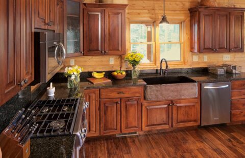 The image showcases an intricately designed kitchen featuring our high-quality wooden cabinets and elegant granite countertops, epitomizing the rustic charm of our log homes.