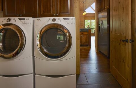 The image showcases a spacious laundry room in one of our log homes, equipped with two efficient washer and dryer units.