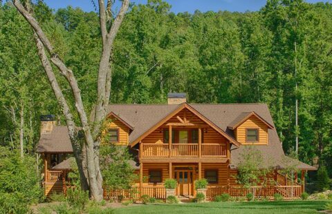 The image showcases our beautifully crafted log home nestled serenely in the heart of a lush, vibrant forest.