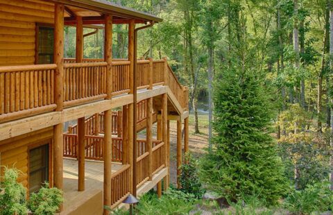 The image portrays a charming, rustic log cabin balcony overlooking the serene wilderness.