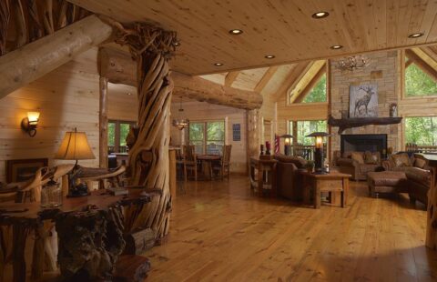 The image showcases a spacious living room featuring rustic charm and warm ambiance, perfectly designed within one of our high-quality log homes.