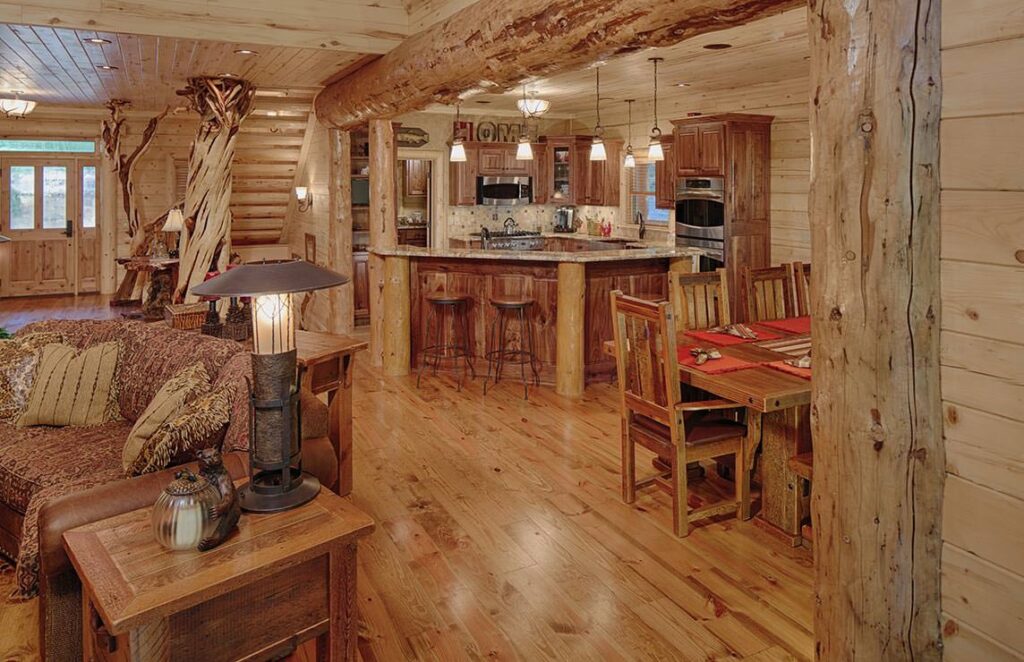 The image showcases a warm and inviting open concept living room and dining area within our meticulously crafted log cabin.