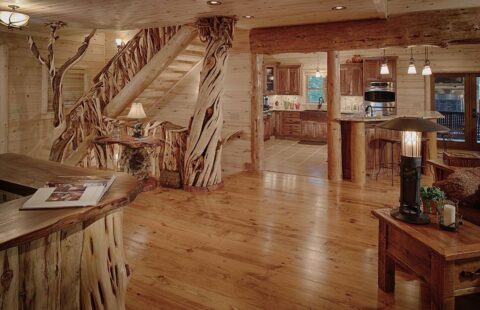 The image features a beautifully crafted log home, showcasing a rustic staircase leading to the upper level and a spacious living room with traditional furnishings.