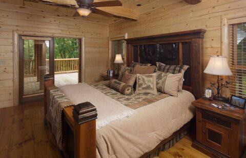 The image showcases a cozy bedroom nestled in one of our beautifully crafted log cabins, complete with a rustic ceiling fan.