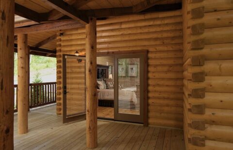 The image features a beautiful, charming front porch of a meticulously handcrafted log cabin.