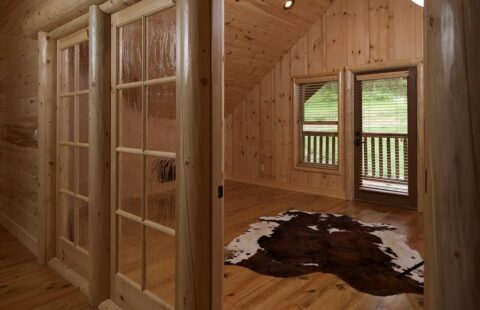 The image portrays a comfortably designed room inside one of our log cabins, featuring a striking cowhide rug.