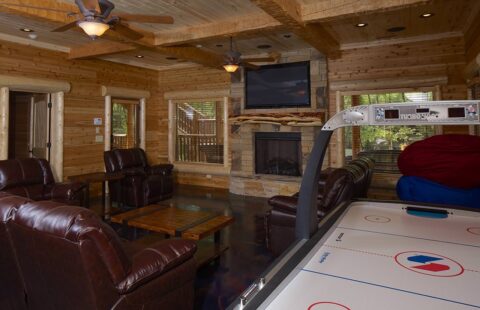 Our log home showcases a spacious living room featuring an air hockey table and comfortable couches.