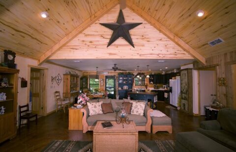 The image showcases a cozy living room in one of our log homes featuring a unique star design on the ceiling.