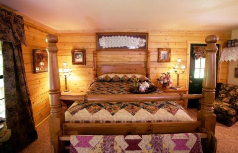 The image showcases a beautifully crafted four-poster bed situated in the cozy setting of our expertly constructed log cabin.