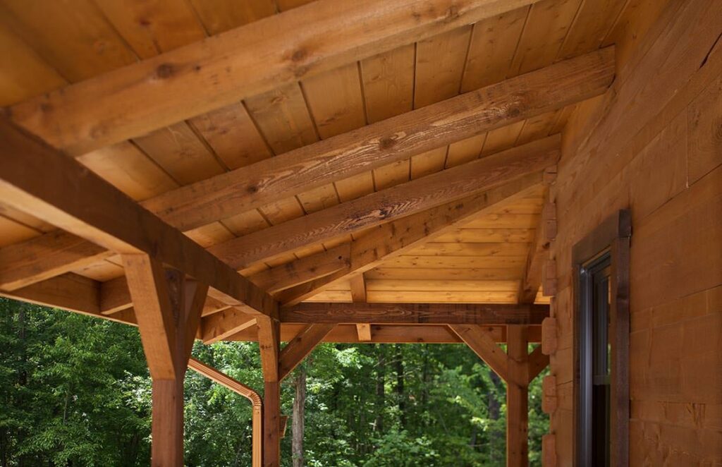 The image showcases a beautifully crafted wooden porch featuring robust wooden beams and intricately designed windows, exemplifying our company's dedication to quality log home craftsmanship.
