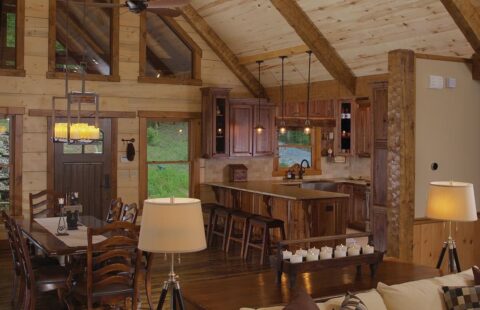 The image showcases an elegantly furnished living room and dining room set in the cozy ambiance of our beautifully constructed log cabin.