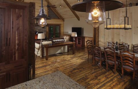 The image showcases a beautifully crafted open-concept living and dining room space in one of our manufactured log cabins.