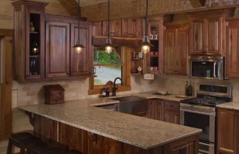 The image showcases a beautifully crafted log home kitchen, featuring high-quality wooden cabinets and stunning granite countertops.