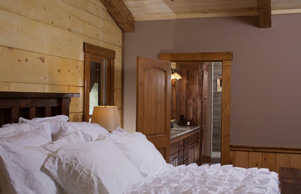 The image showcases a cozy bedroom within our log home, featuring a comfortable bed and sturdy wooden dresser.