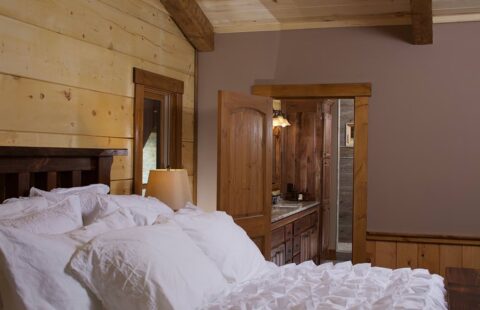 The image showcases a cozy bedroom within our log home, featuring a comfortable bed and sturdy wooden dresser.