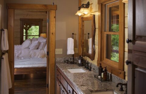 The image showcases an elegantly designed bathroom in one of our log cabins, featuring two sinks and a spacious mirror.