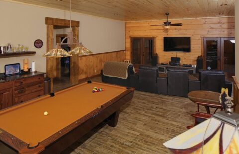 The image showcases a cozy living room in one of our log homes, equipped with entertainment amenities such as a pool table and a television.