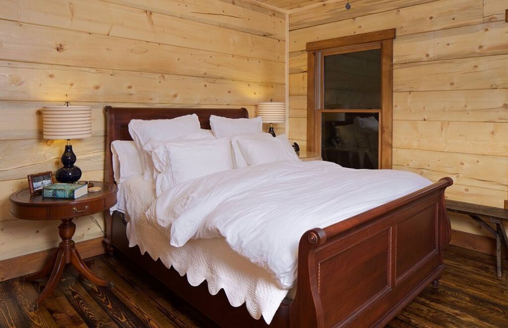 The image depicts a cozy bedroom within our log cabin, showcasing the beautiful, warm wooden walls that add to the rustic charm.