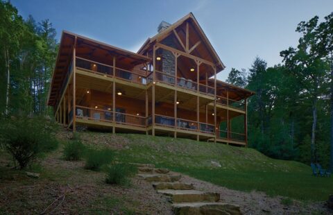 The image captures a spacious log cabin nestled within the serene tranquility of a forest setting, epitomizing our company's commitment to creating sturdy, rustic homes that seamlessly blend with nature.