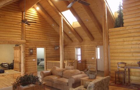 The image showcases a cozy, rustic living room inside one of our beautifully crafted log cabins.