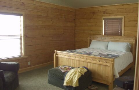 The image showcases a cozy, inviting bed nestled in the rustic charm of our log home's bedroom.