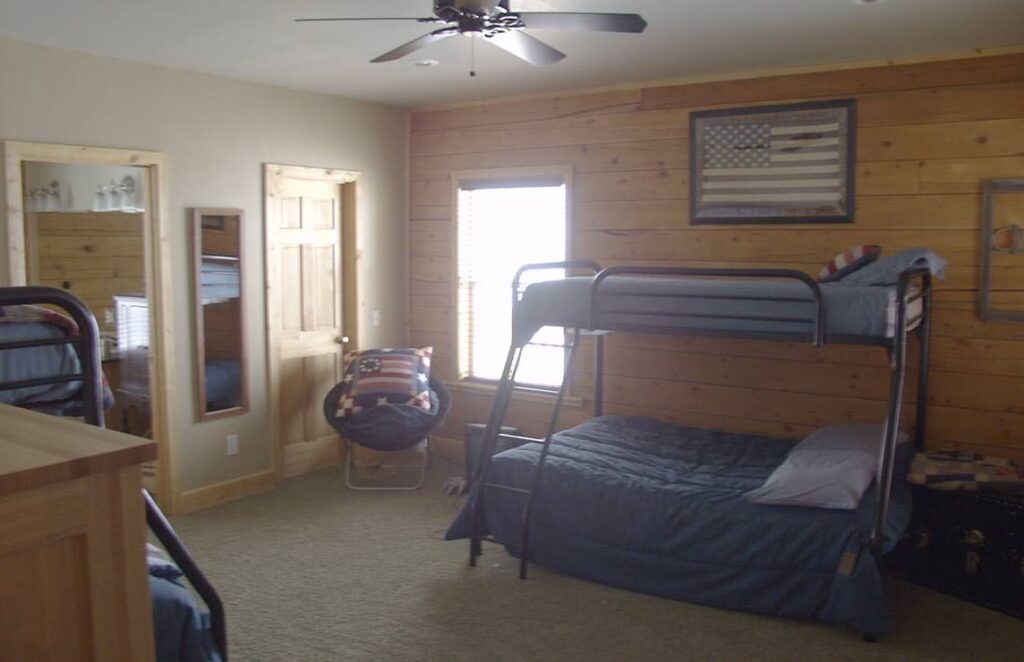 The image showcases a beautifully crafted wooden bunk bed sitting elegiously in the corner of one of our log home's cozy interior rooms.