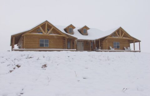 Our product image features a stunning snowy log home nestled on a hill, beautifully crafted by our skilled artisans.